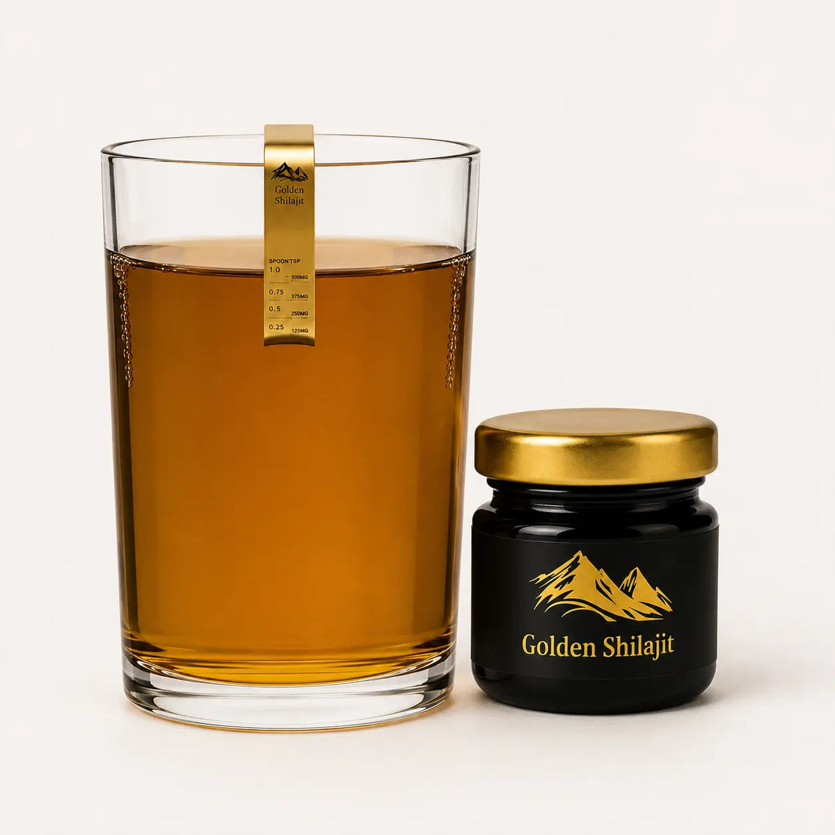 A clear glass tumbler filled with amber liquid and a small black jar with a gold lid labeled Golden Shilajit, photographed on a clean white background.