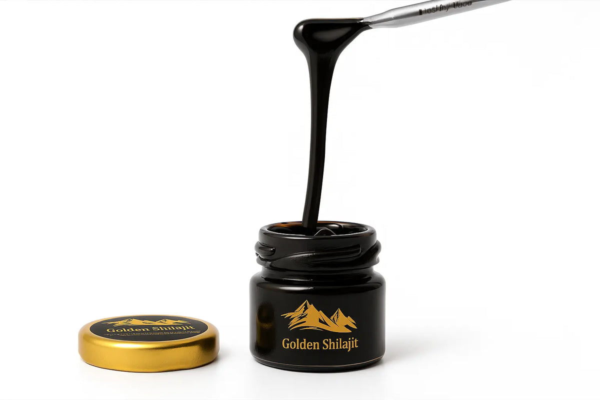 A small black jar labeled 'Golden Shilajit' with its gold lid placed beside it on a white background, showing a thick black paste being drawn up through the open jar with a metal tool.